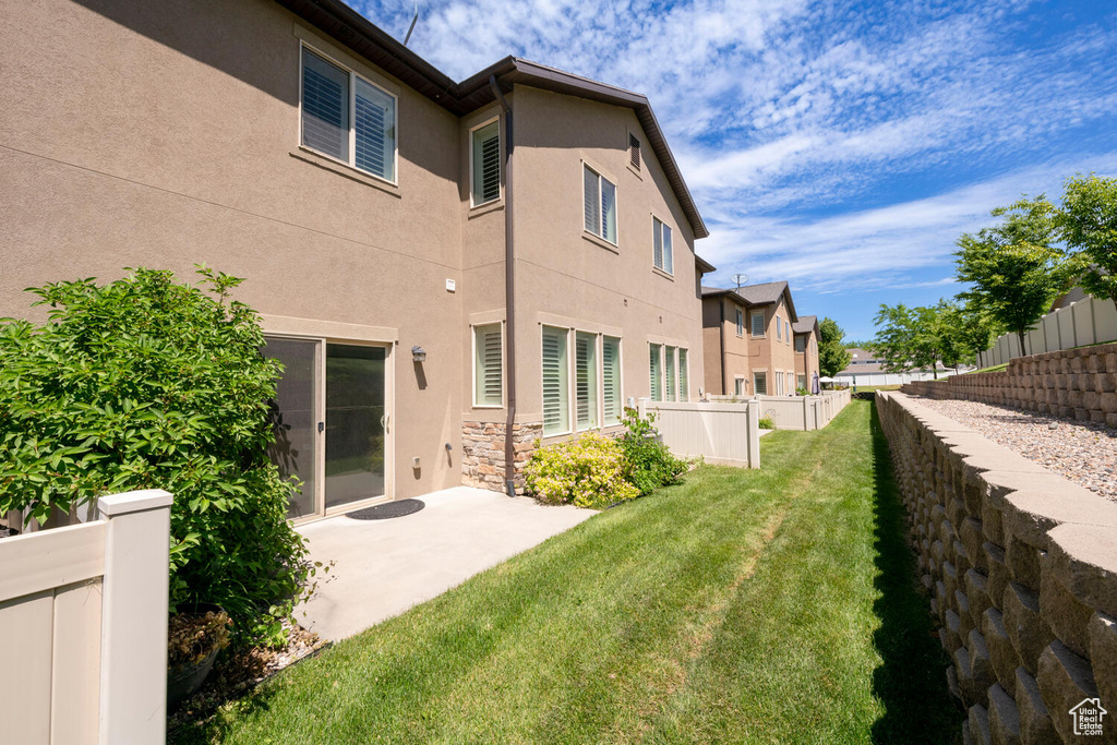 Back of property with stucco siding, a patio area, and stone siding