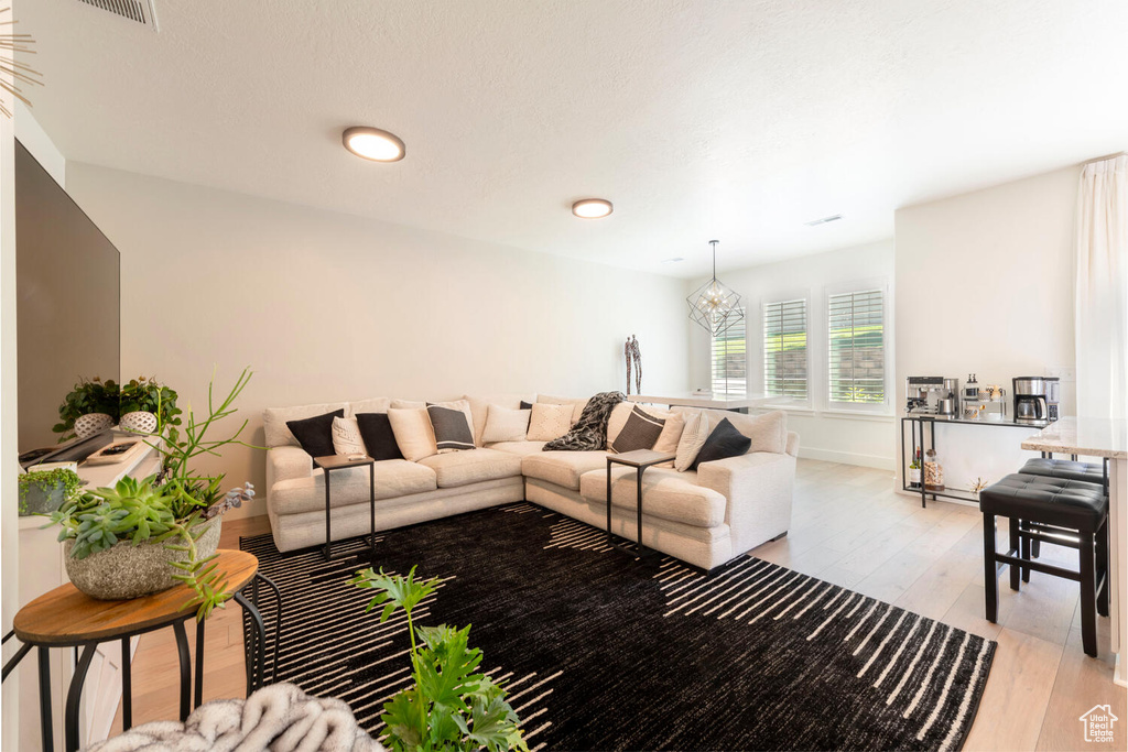 Living area with light wood-style flooring, a chandelier, and baseboards