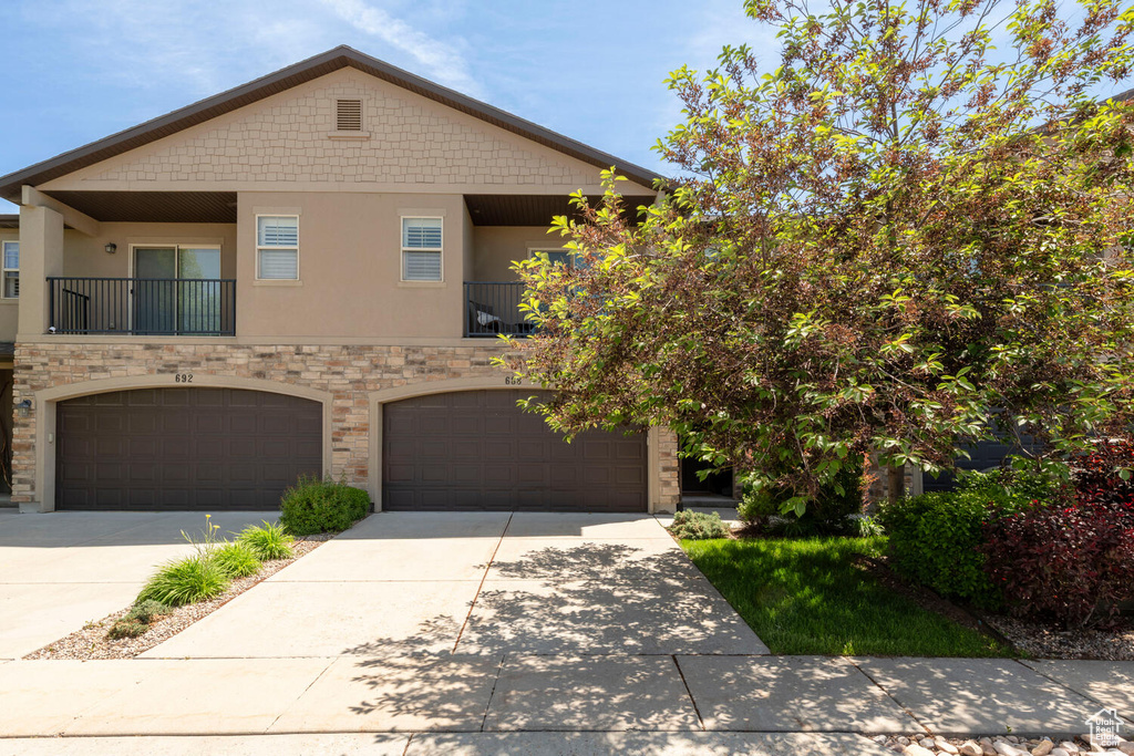 Townhome / multi-family property featuring stucco siding, concrete driveway, an attached garage, and stone siding