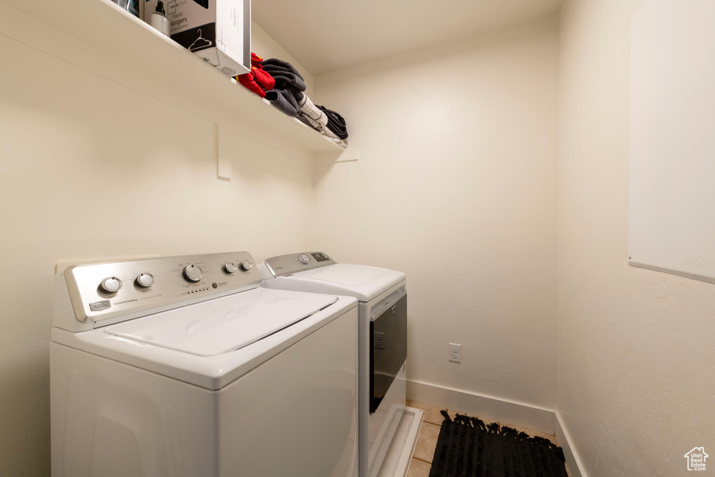 Washroom with independent washer and dryer, baseboards, and light tile patterned flooring