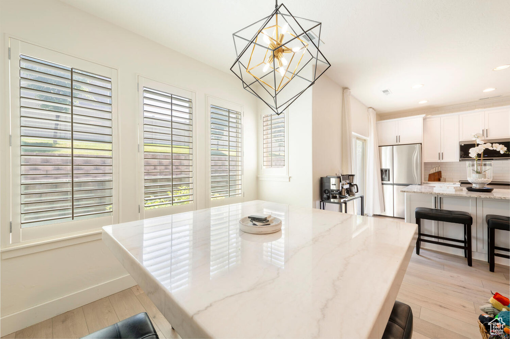 Dining space with a chandelier, light wood-type flooring, recessed lighting, and baseboards