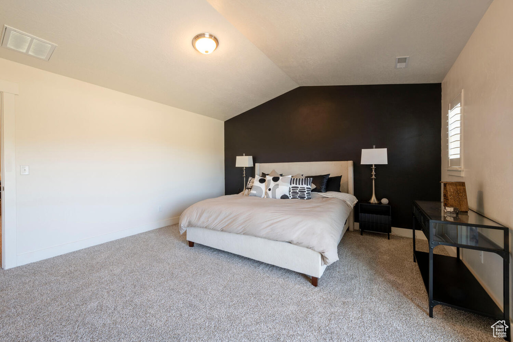 Bedroom with vaulted ceiling, carpet, and baseboards