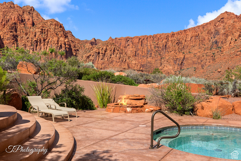 View of swimming pool featuring a fire pit, a patio, an in-ground hot tub, and a mountain view