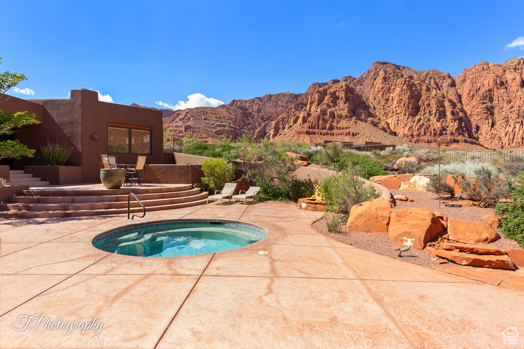 View of pool with an in-ground hot tub, a patio area, and a mountain view