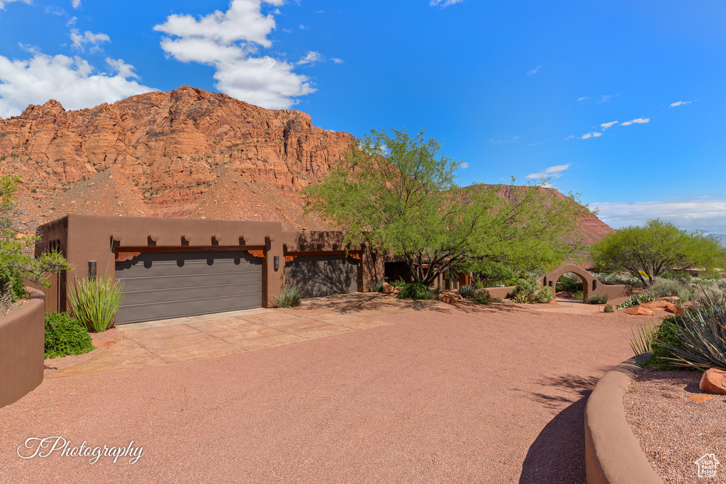 View of front facade featuring a garage, a mountain view, driveway, and stucco siding