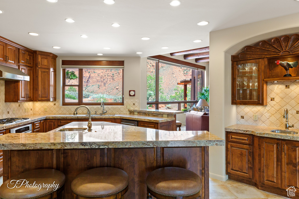 Kitchen featuring a sink, recessed lighting, backsplash, a kitchen bar, and an island with sink