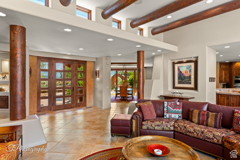 Living area with recessed lighting, light tile patterned floors, beam ceiling, and a towering ceiling