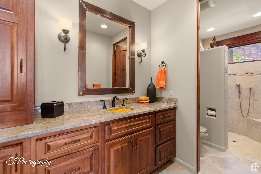 Full bathroom with toilet, a tile shower, vanity, tile patterned floors, and recessed lighting