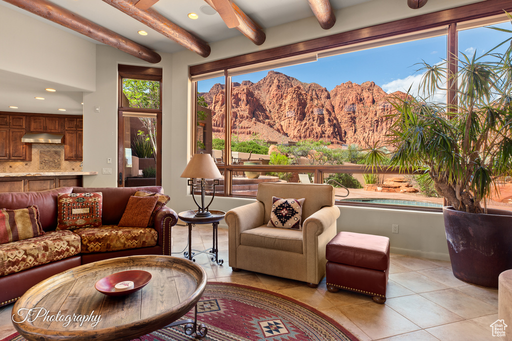 Living room with a mountain view, light tile patterned floors, beam ceiling, recessed lighting, and baseboards