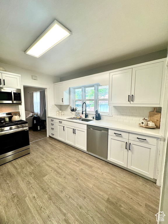 Kitchen featuring stainless steel appliances, a sink, tasteful backsplash, and white cabinetry