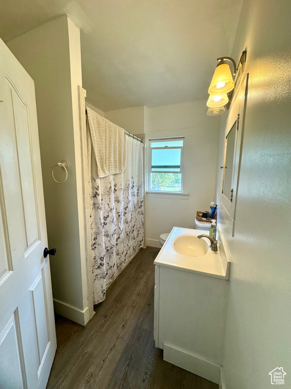 Bathroom with vanity, wood finished floors, toilet, baseboards, and a shower with curtain
