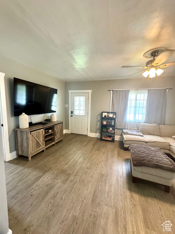 Living area with wood finished floors, baseboards, and a ceiling fan