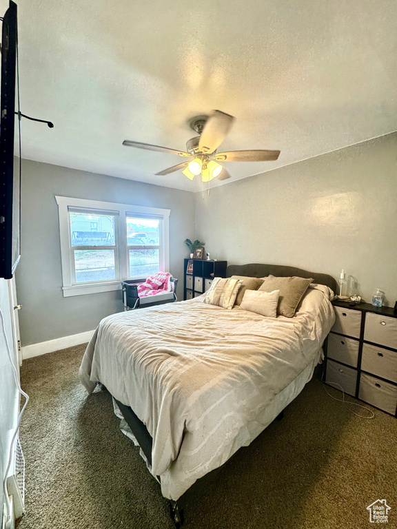 Carpeted bedroom with ceiling fan, baseboards, and a textured ceiling