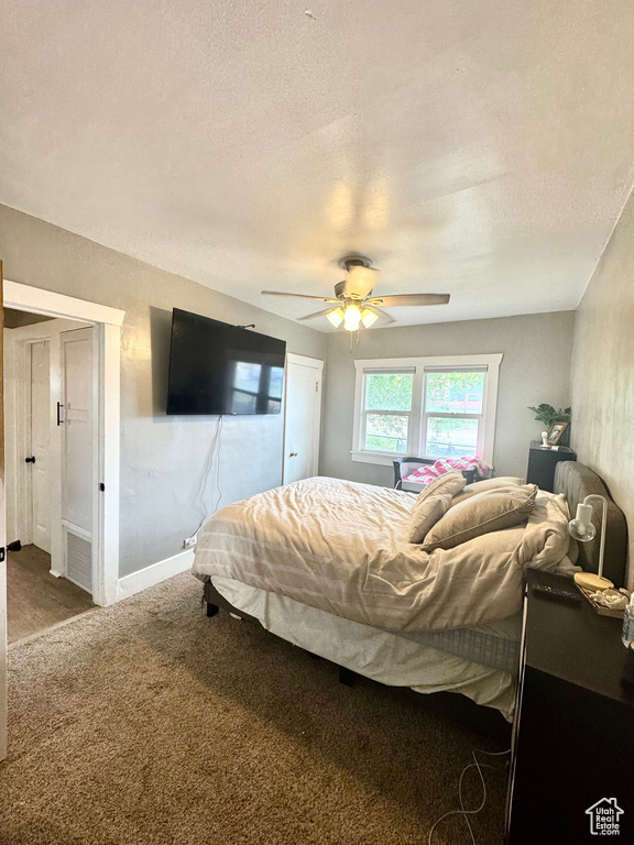 Bedroom with carpet floors, ceiling fan, baseboards, and a textured ceiling