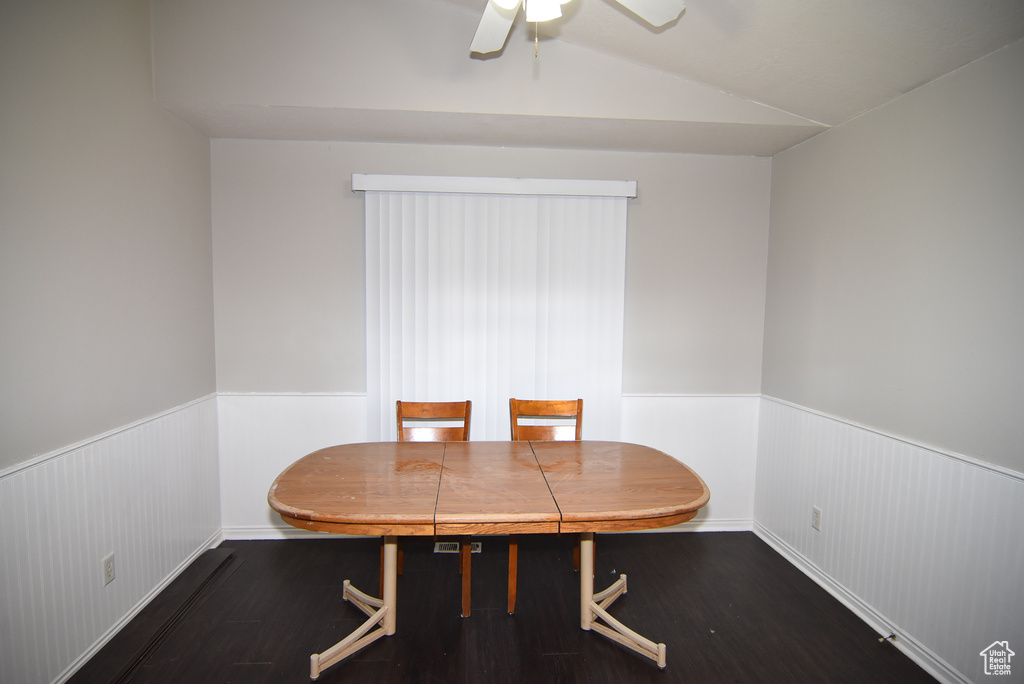 Dining room featuring wainscoting, wood finished floors, lofted ceiling, and a ceiling fan