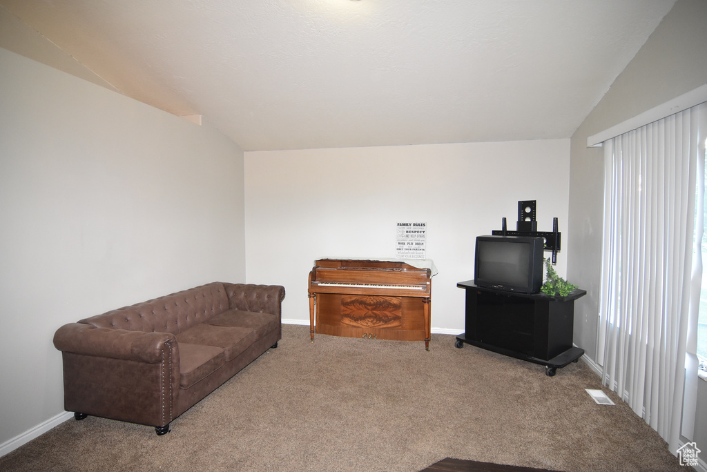Living room featuring carpet flooring, baseboards, and lofted ceiling
