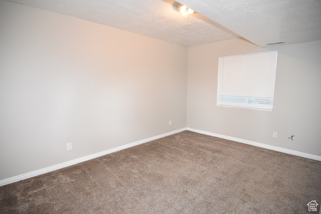 Unfurnished room with carpet flooring, baseboards, and a textured ceiling