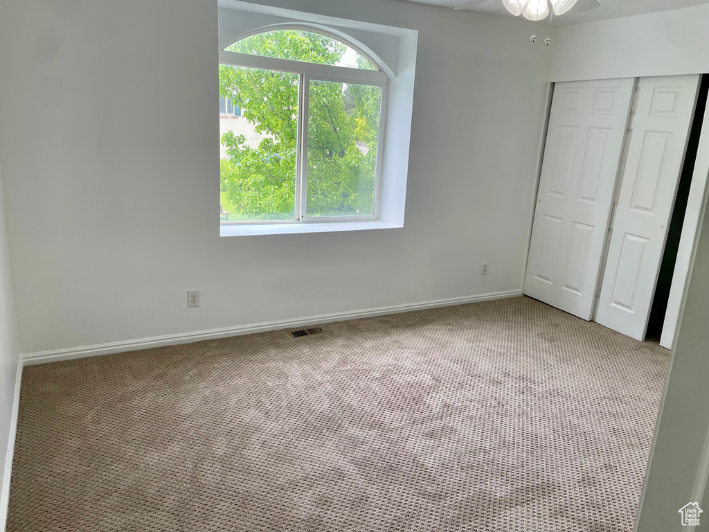 Unfurnished bedroom featuring light carpet, a closet, baseboards, and a ceiling fan