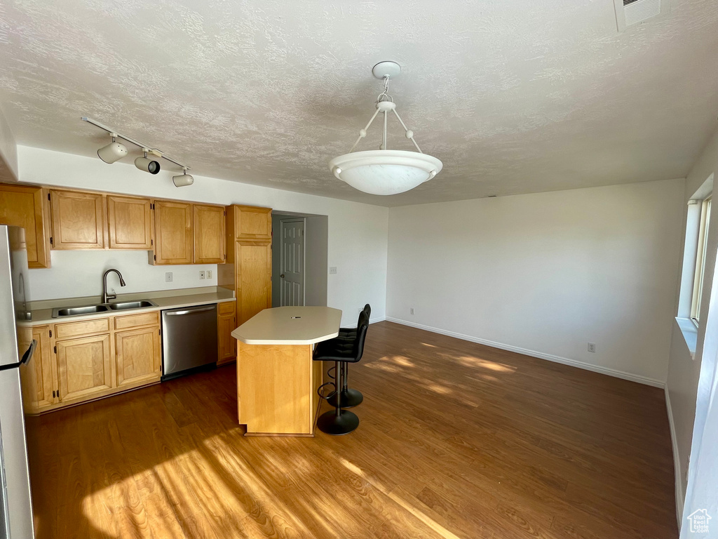 Kitchen featuring dishwasher, freestanding refrigerator, light countertops, dark wood-style flooring, and a kitchen island