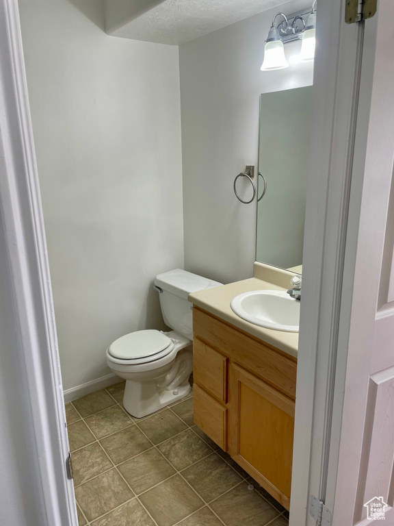 Half bathroom featuring toilet, vanity, and tile patterned floors