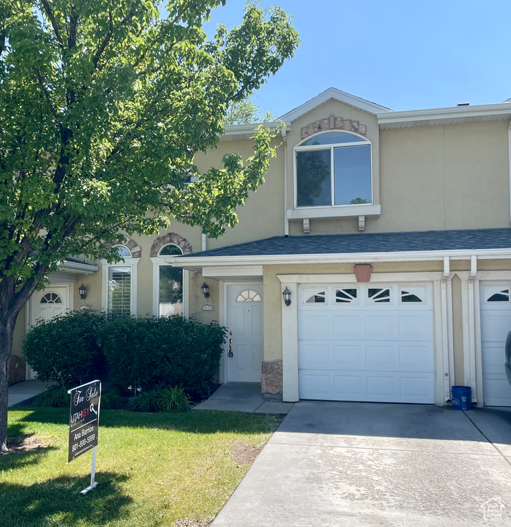 View of front of property with an attached garage, a front lawn, concrete driveway, stucco siding, and stone siding