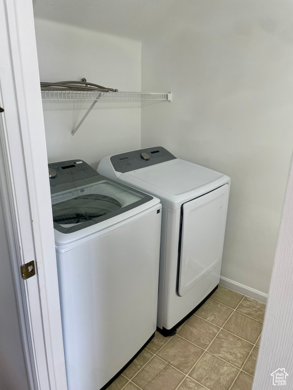Laundry room featuring washing machine and clothes dryer, baseboards, and light tile patterned floors