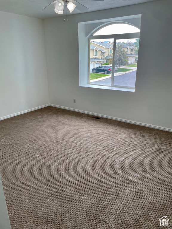 Empty room with carpet floors, a ceiling fan, and baseboards