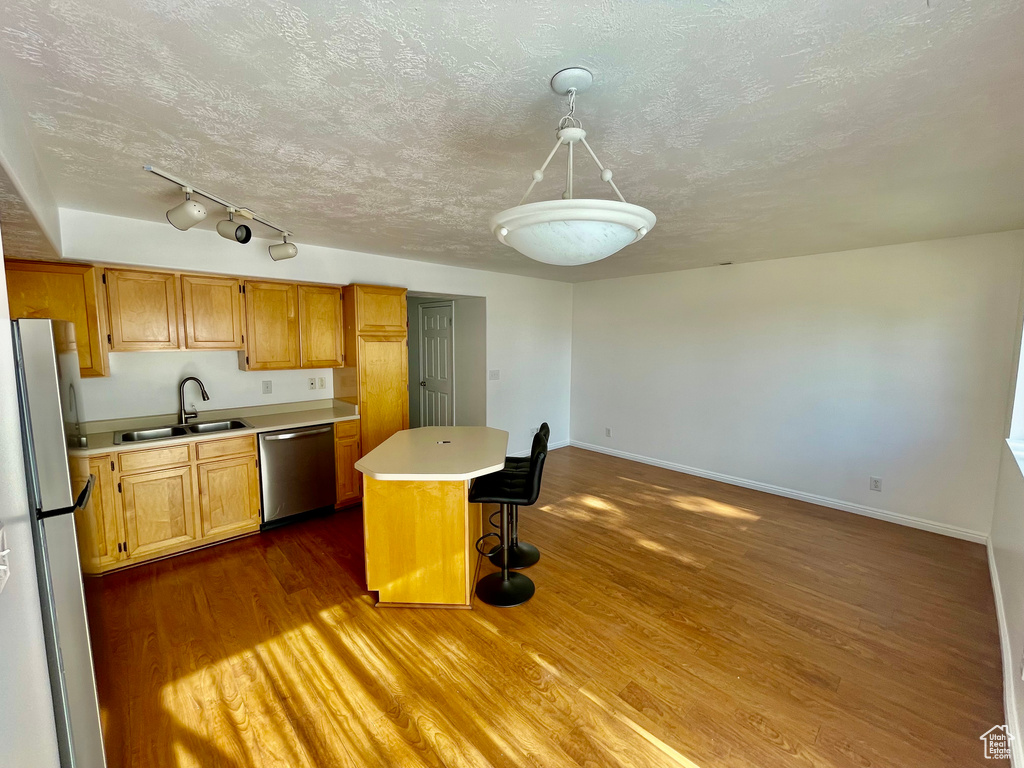 Kitchen featuring dishwasher, freestanding refrigerator, light countertops, dark wood finished floors, and a kitchen island