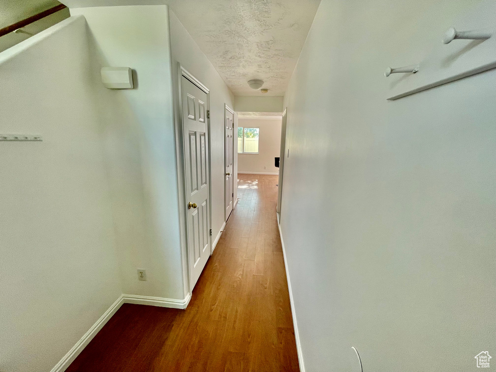Hall with wood finished floors and a textured ceiling