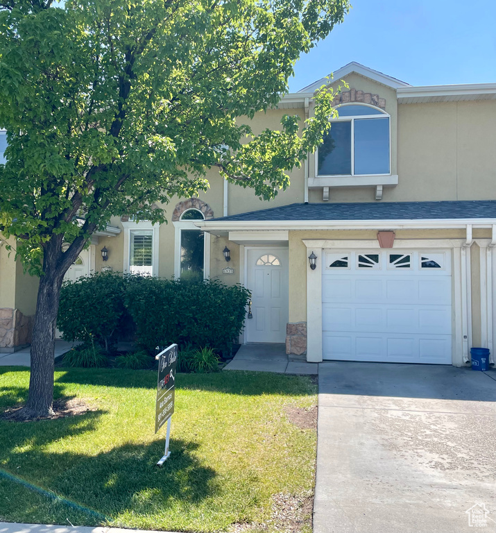 Multi unit property featuring an attached garage, a front lawn, stucco siding, and concrete driveway
