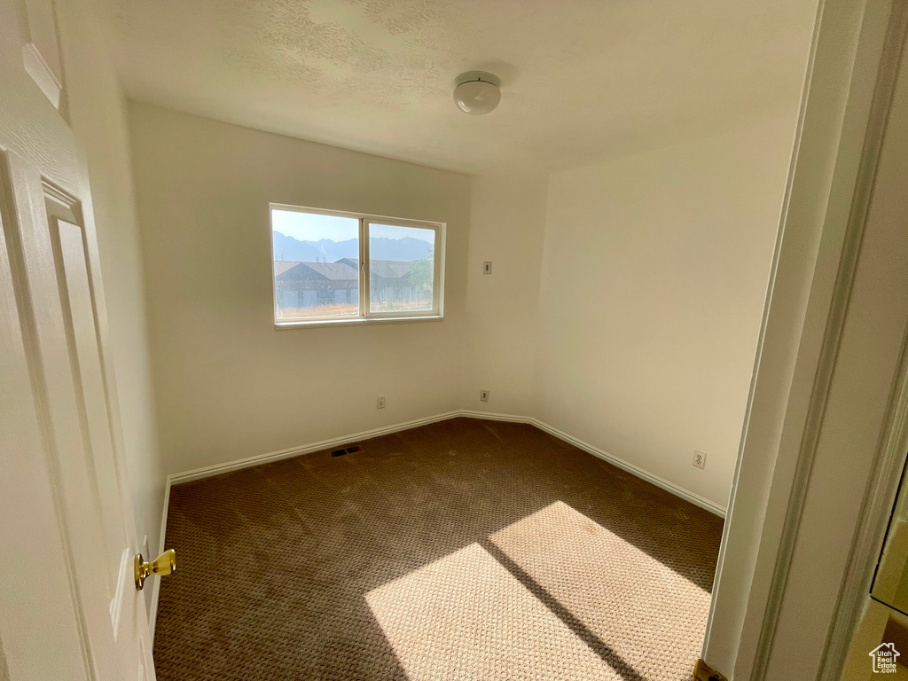 Empty room with dark carpet and baseboards