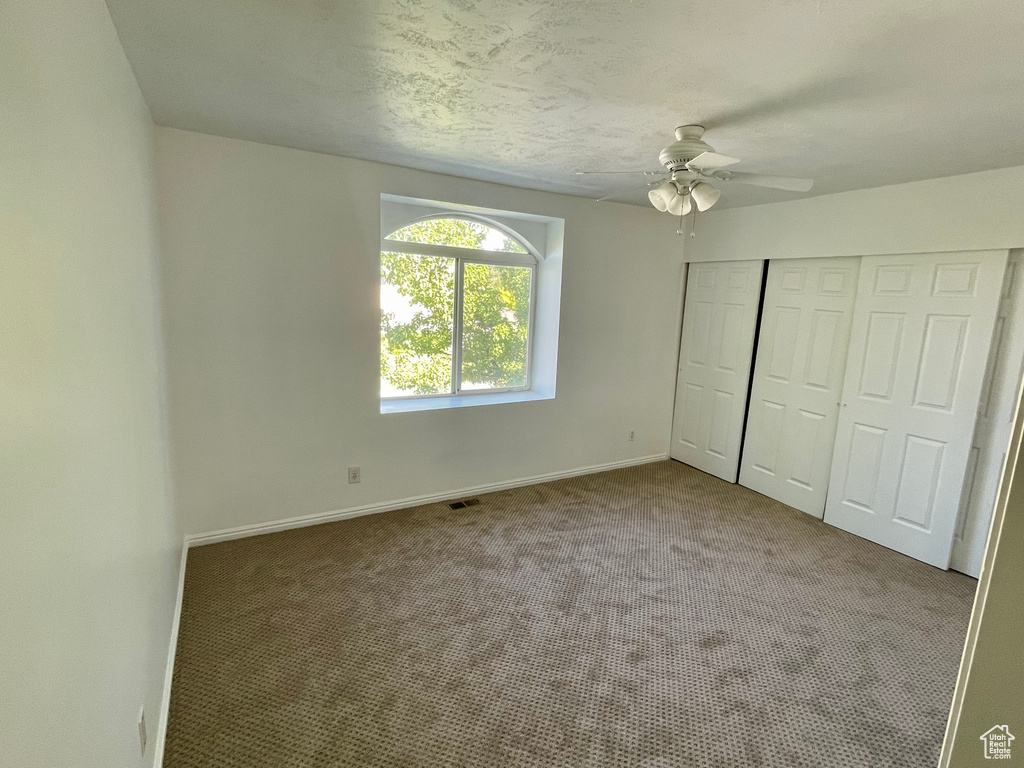 Unfurnished bedroom featuring carpet, a closet, and a ceiling fan