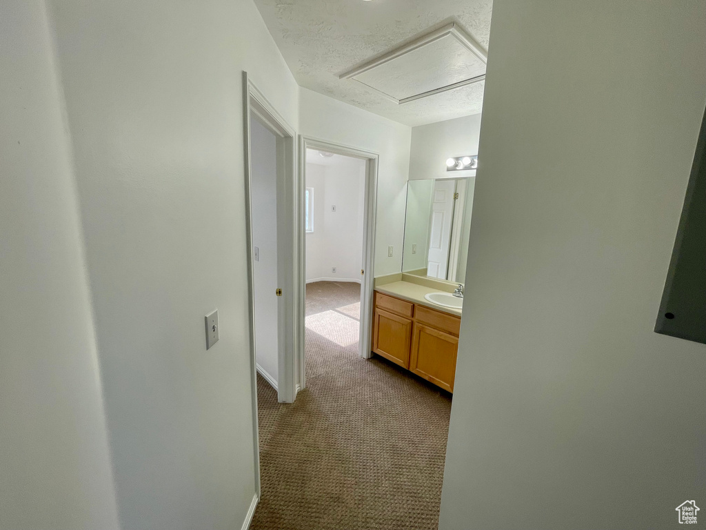 Hall featuring dark colored carpet and a textured ceiling