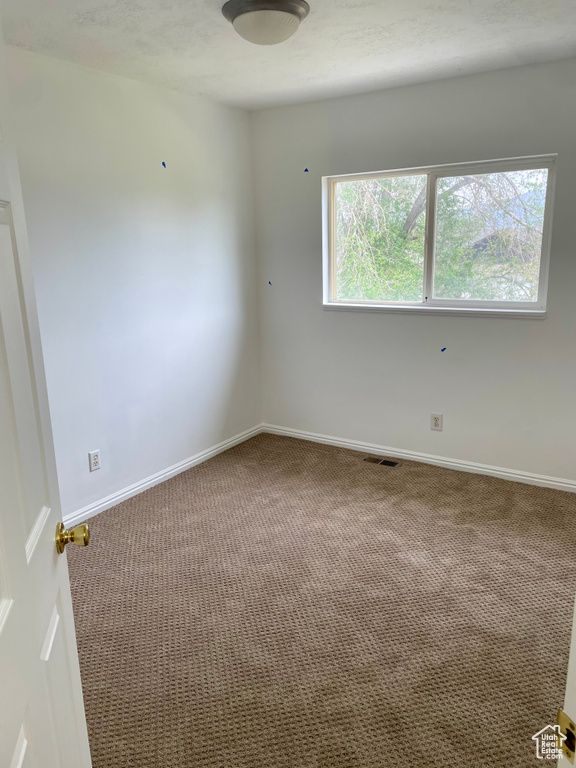 Empty room featuring carpet and baseboards
