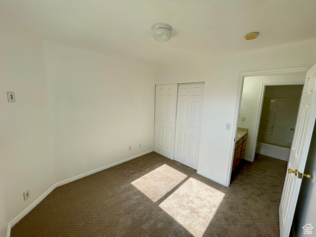 Unfurnished bedroom with dark carpet and a closet