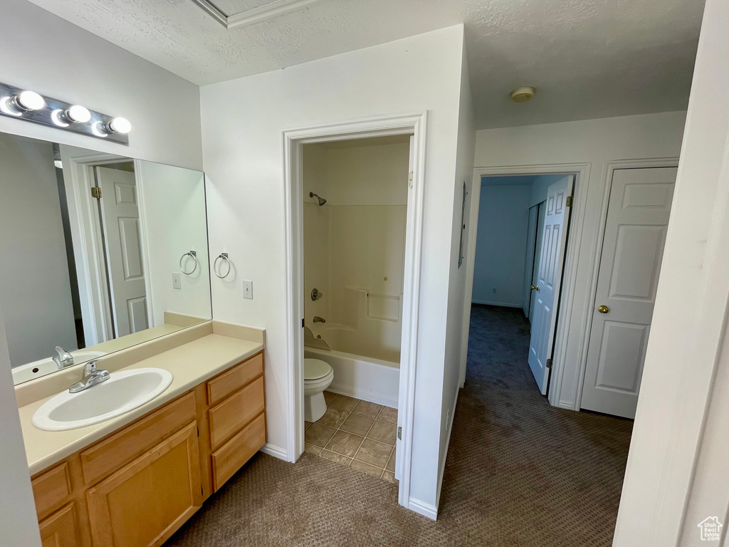 Bathroom featuring vanity, washtub / shower combination, a textured ceiling, and tile patterned floors