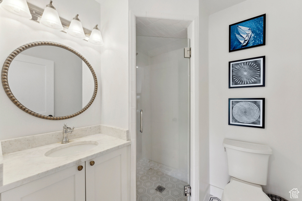 Bathroom featuring vanity, a stall shower, toilet, and tile patterned flooring