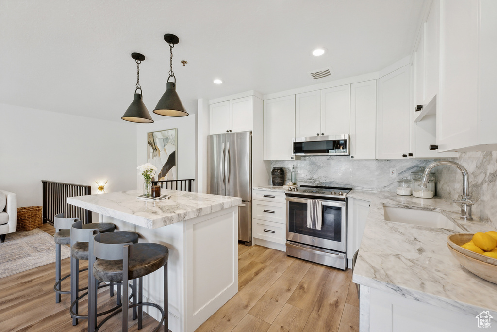 Kitchen featuring stainless steel appliances, a sink, backsplash, a center island, and a kitchen bar