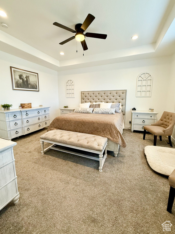Carpeted bedroom with a raised ceiling, recessed lighting, and ceiling fan