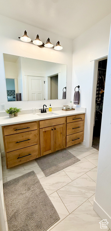 Full bathroom with marble finish flooring, vanity, and a walk in closet