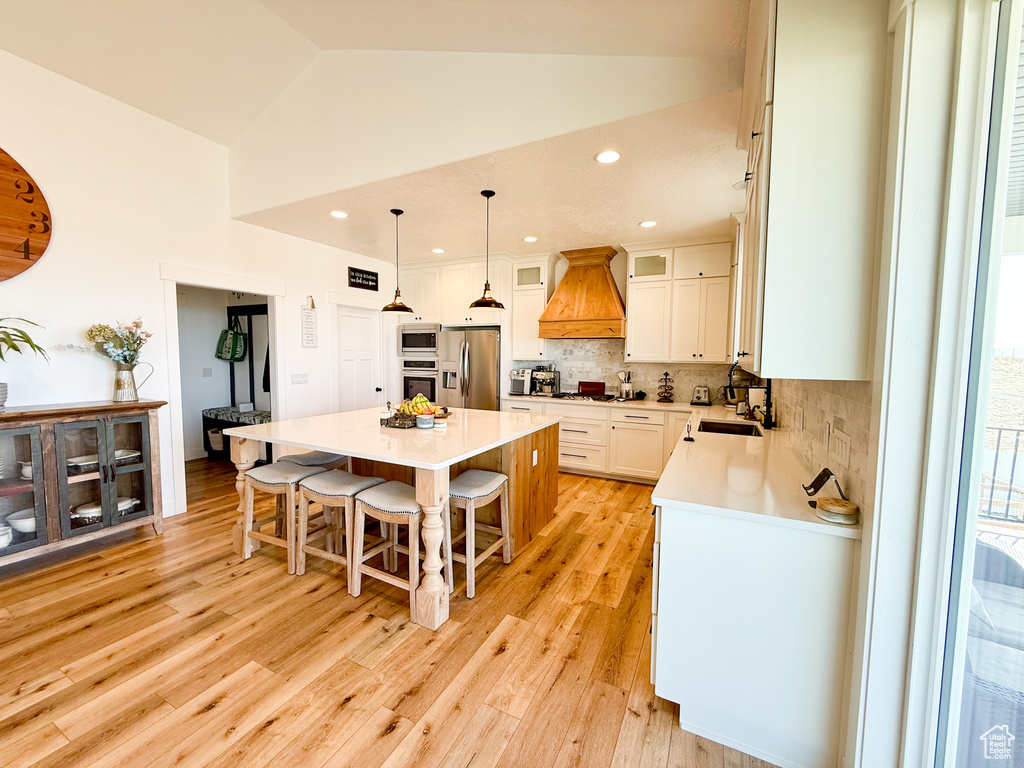 Kitchen with stainless steel appliances, premium range hood, a center island, a kitchen bar, and decorative backsplash