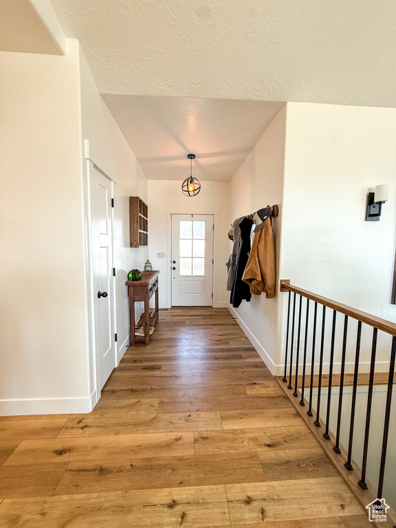 Doorway with light wood-type flooring, baseboards, and a textured ceiling
