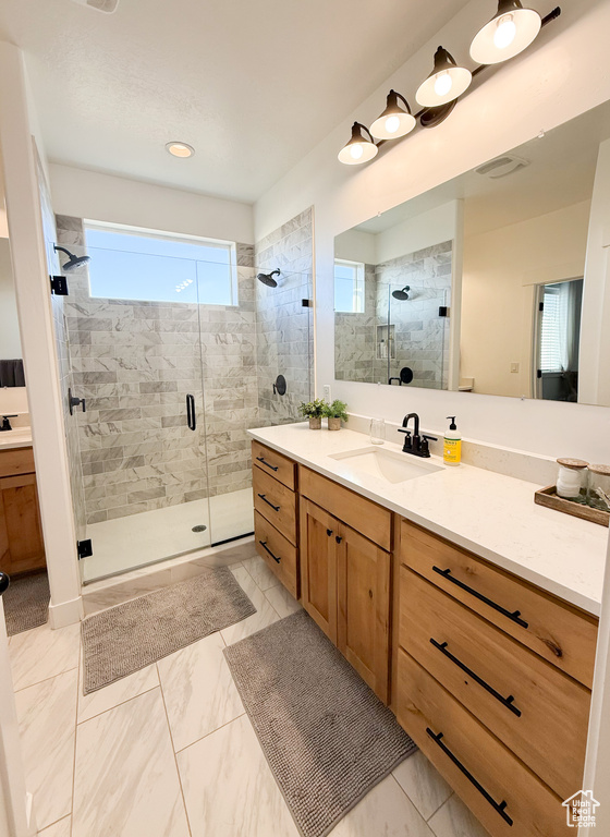 Full bathroom featuring a stall shower, vanity, and marble look tiles