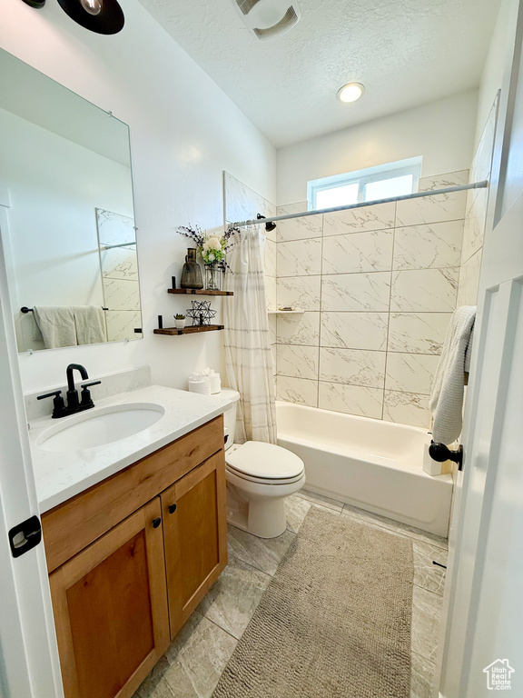 Bathroom with shower / bathtub combination with curtain, vanity, toilet, and a textured ceiling