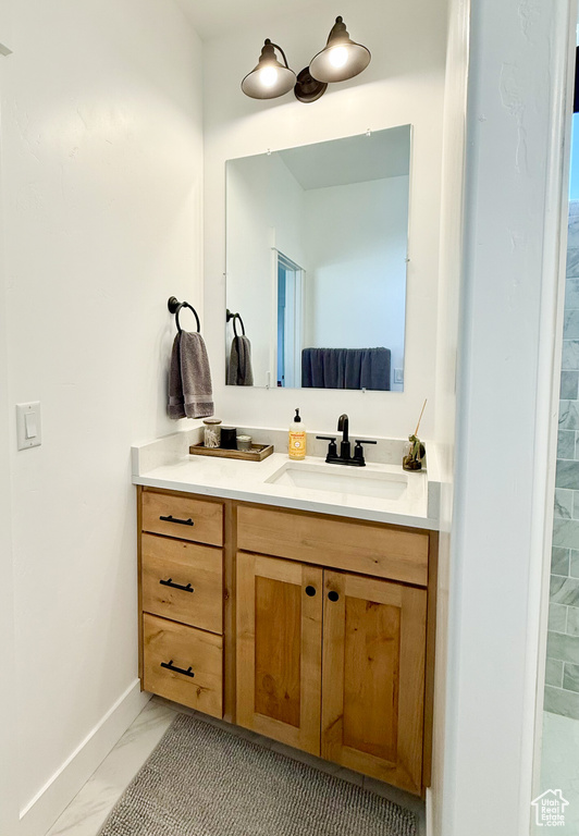 Bathroom featuring marble look tile flooring, vanity, and baseboards