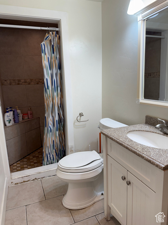 Full bathroom featuring vanity, a shower stall, toilet, and tile patterned floors