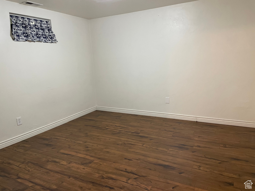 Spare room featuring dark wood finished floors and baseboards