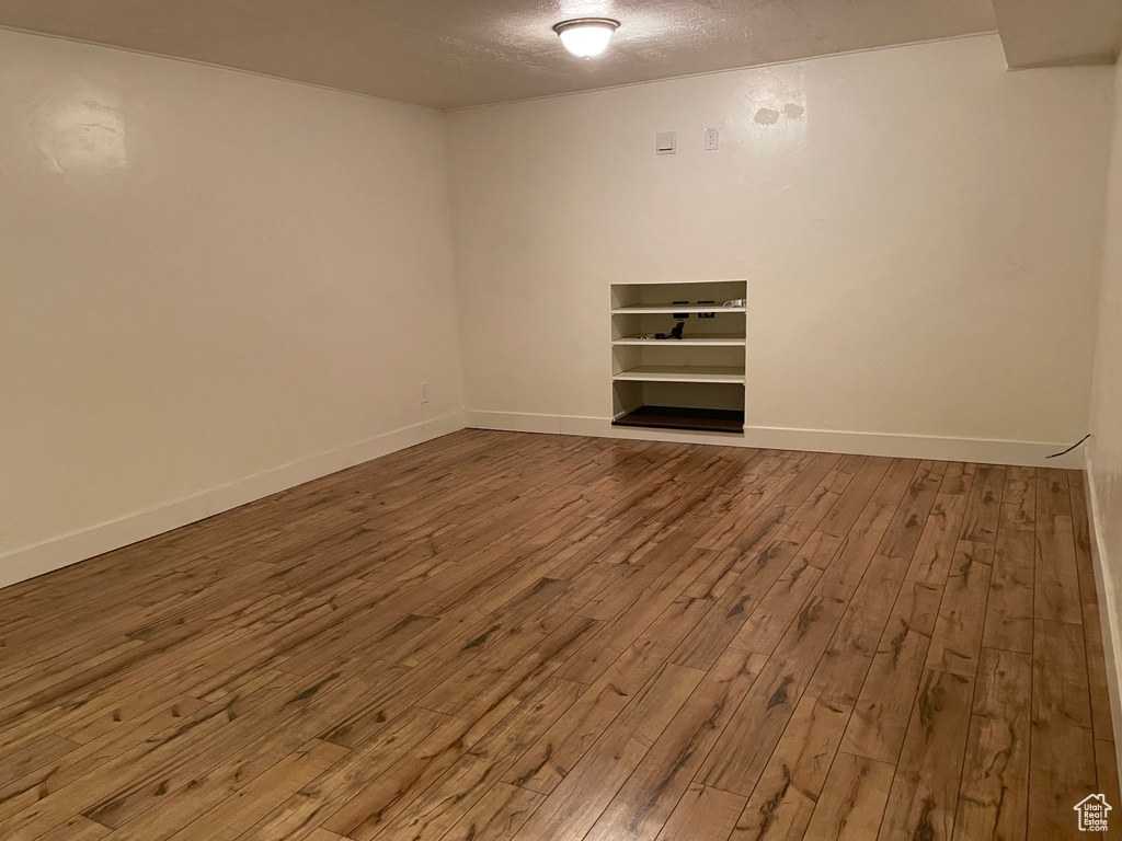 Spare room featuring wood-type flooring, baseboards, and a textured ceiling