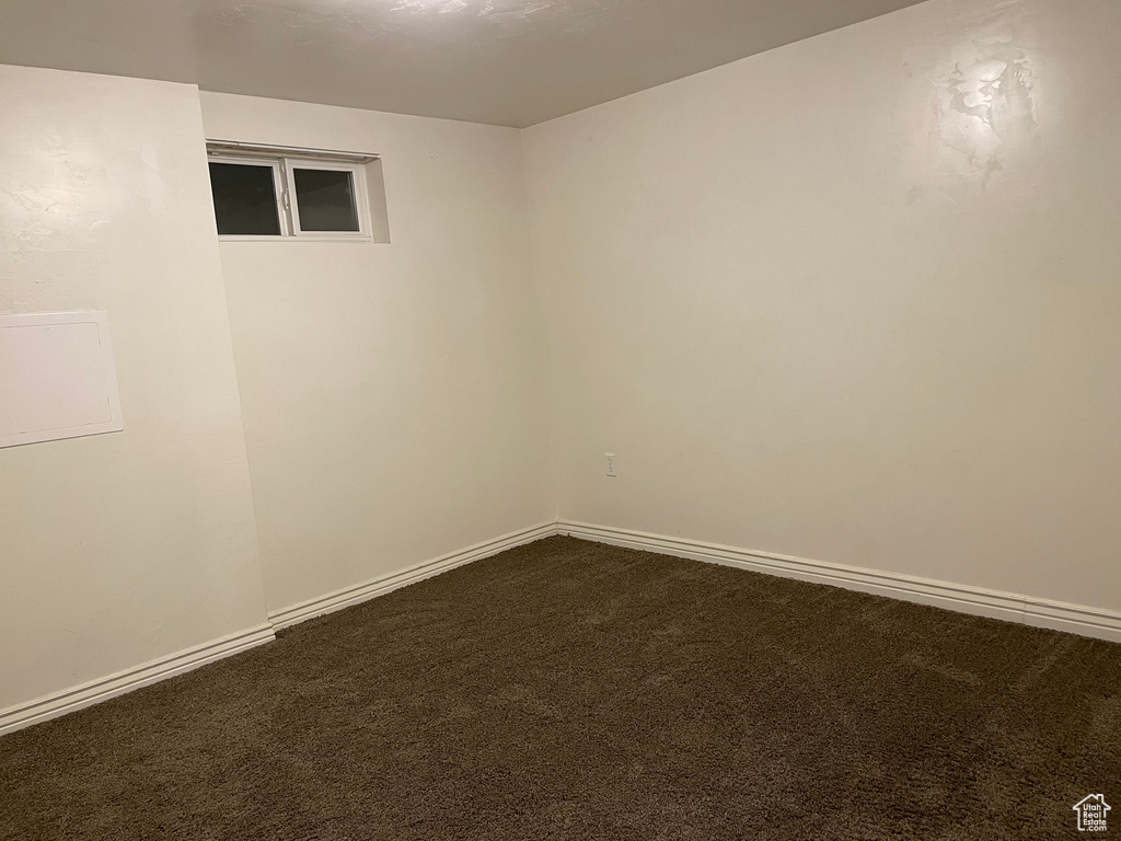 Spare room with dark carpet and baseboards