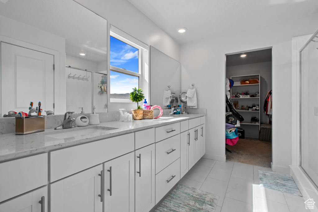 Bathroom featuring a stall shower, double vanity, a walk in closet, tile patterned flooring, and recessed lighting